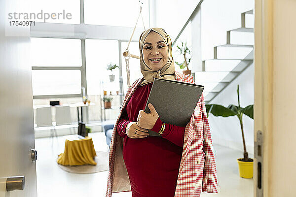 Happy pregnant woman with file folder at home