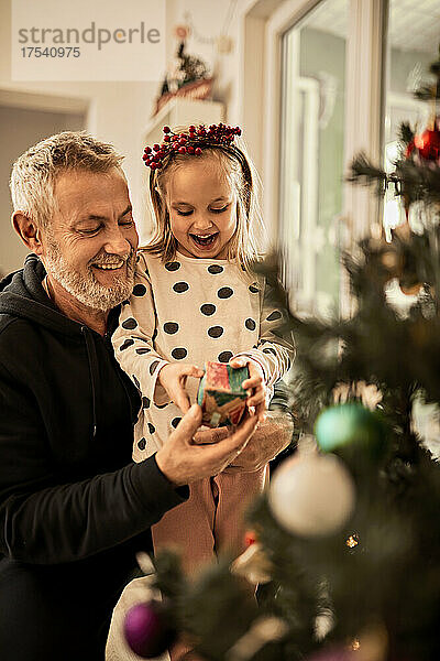 Grandfather giving gift to granddaughter on christmas at home