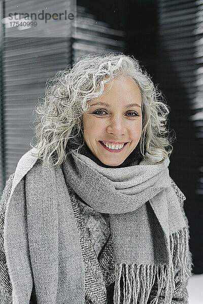 Lächelnde Frau mit grauen Haaren  die warme Kleidung trägt