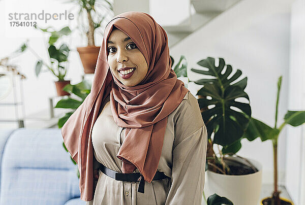 Smiling woman wearing hijab in living room
