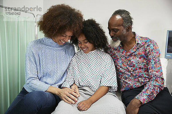 Happy family sitting together on bed at hospital