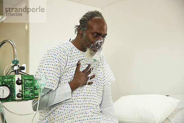 Patient touching chest wearing oxygen mask in medical room