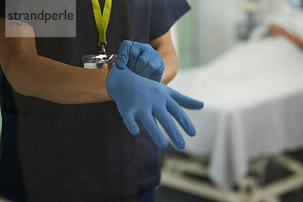 Healthcare worker wearing glove in medical room