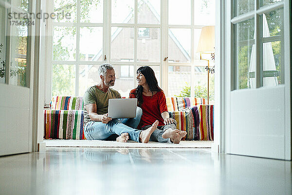 Heterosexual couple with laptop sitting at home