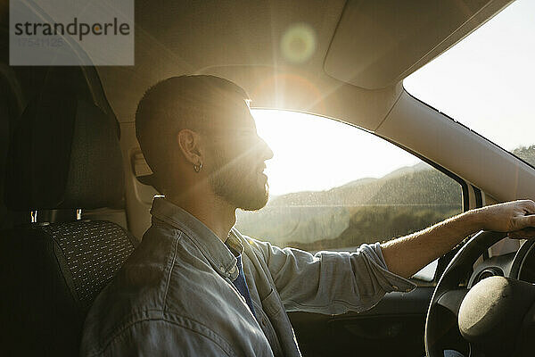Young man driving van on sunny day