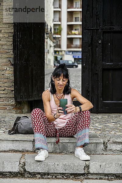 Woman using mobile phone sitting on steps