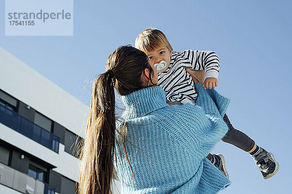 Mother carrying son in front of blue sky