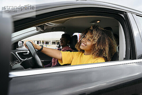 Smiling woman driving car with friend