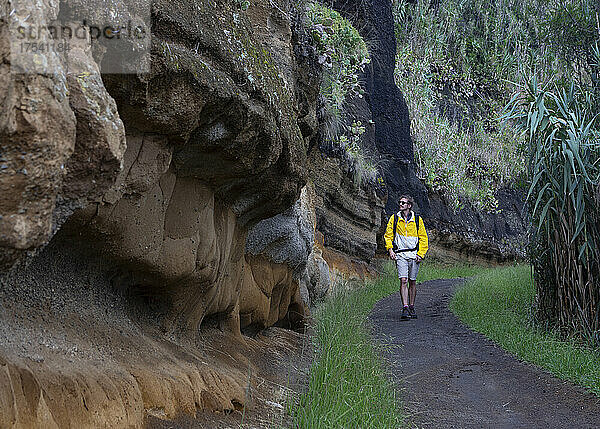 Wanderer mit Rucksack läuft auf der Straße an einer Felsformation vorbei