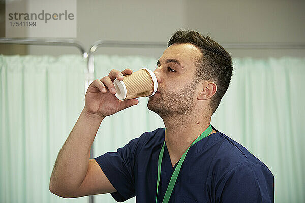 Krankenpfleger trinkt Kaffee im Einwegbecher im Krankenhaus