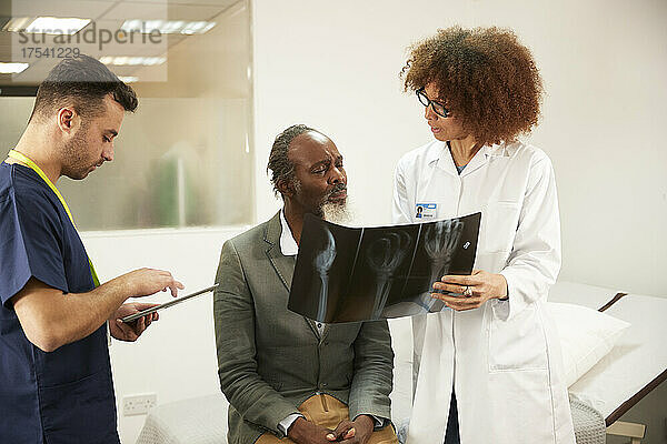 Arzt bespricht Röntgenbericht mit Patient im Krankenzimmer