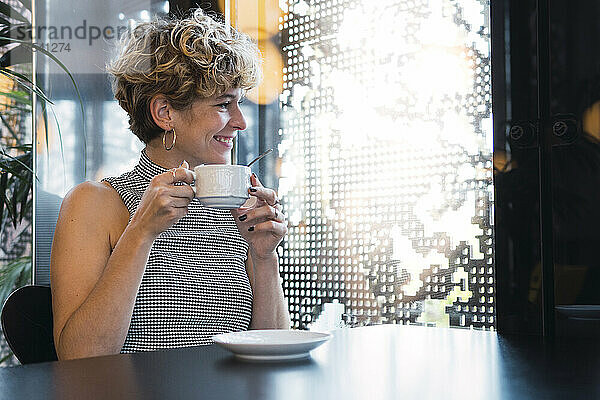 Lächelnde junge Frau mit Kaffeetasse im Café