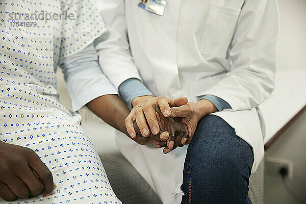 Arzt hält Händchen und tröstet den Patienten im Krankenzimmer
