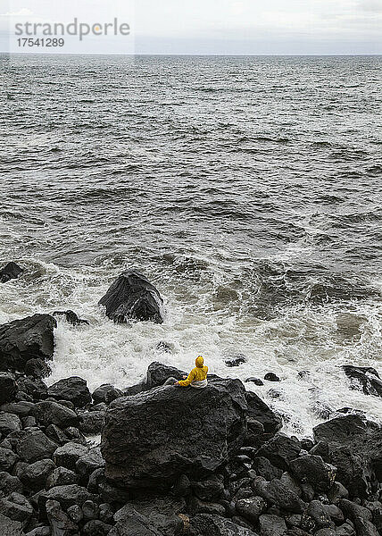 Young man on volcanic rock looking at sea  Rocha Da Relva  San Miguel Island  Azores  Portugal