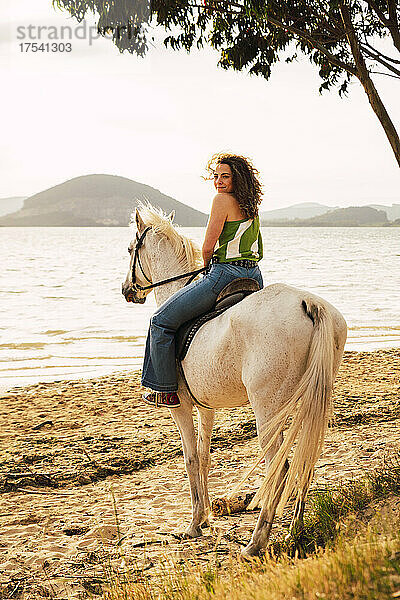 Young woman enjoying horse riding at waterfront