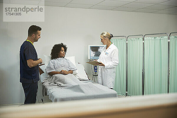 Arzt und Krankenschwester diskutieren mit dem Patienten im Krankenzimmer des Krankenhauses