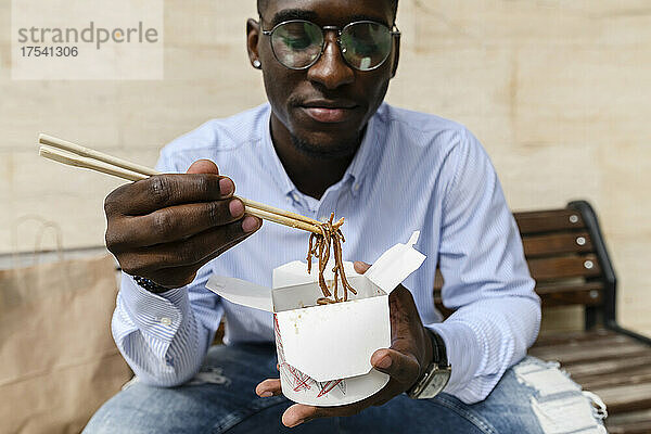 Man having noodles with chopsticks