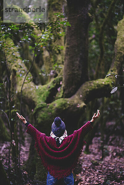 Woman with arms outstretched standing at forest