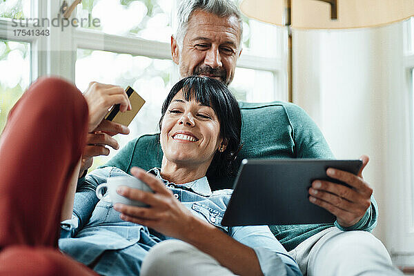 Happy couple with credit card doing online shopping on Tablet PC