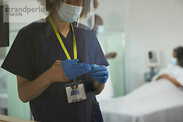 Nurse with face shield wearing surgical glove