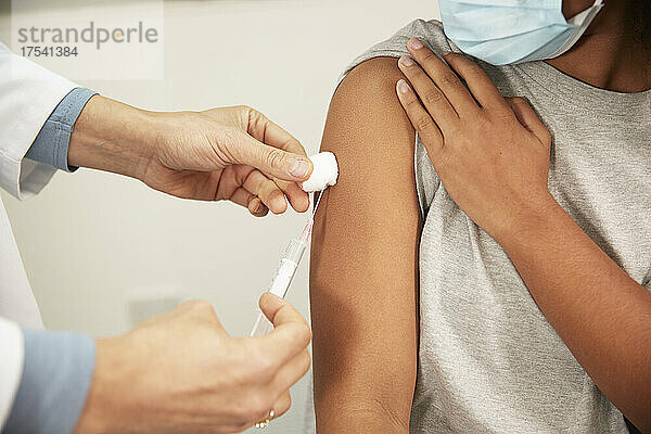 Arzt injiziert Mädchen im Krankenzimmer mit einer Spritze die COVID-19-Impfung