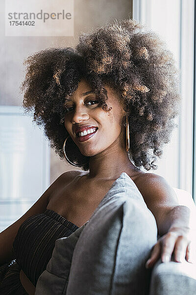 Lächelnde junge Frau mit Afro-Frisur zu Hause