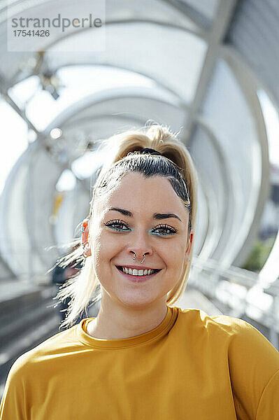 Smiling young woman at bridge on sunny day