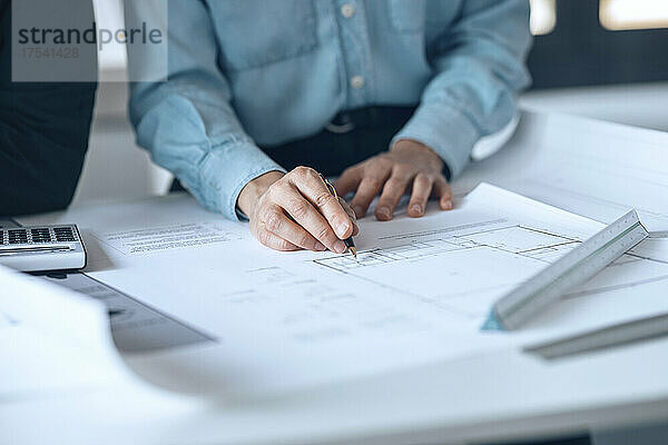 Architekt hält Stift auf Dokument in kleinem Büro
