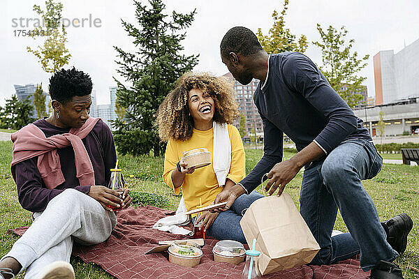 Cheerful friends having picnic in park