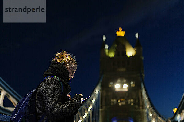 Frau benutzt Mobiltelefon an der berühmten Tower Bridge  London  England  Großbritannien