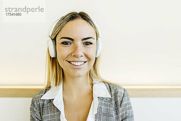 Smiling businesswoman wearing headphones in cafe