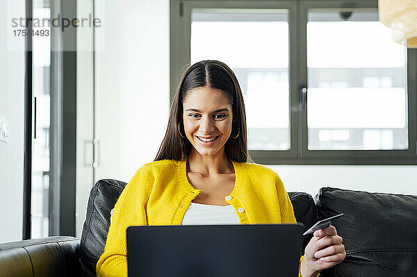 Glückliche Frau beim Online-Shopping am Laptop zu Hause