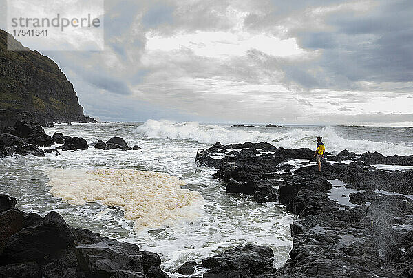 Mann steht auf Felsen in der Nähe des Thermalbeckens in Ponta da Ferraria  San Miguel  Azoren  Portugal