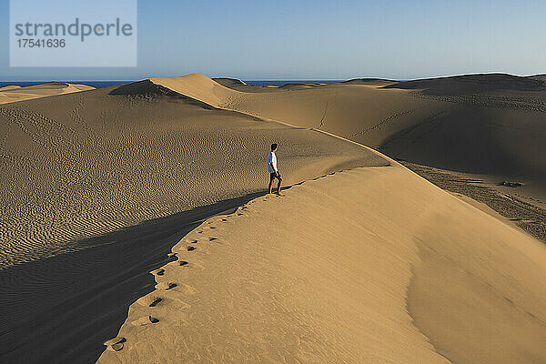 Junger Mann spaziert bei Sonnenuntergang auf einer Sanddüne  Gran Canaria  Kanarische Inseln  Spanien