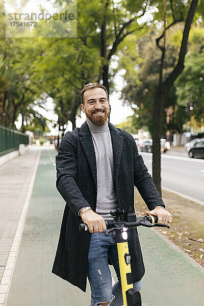 Bearded man with electric push scooter on bicycle lane