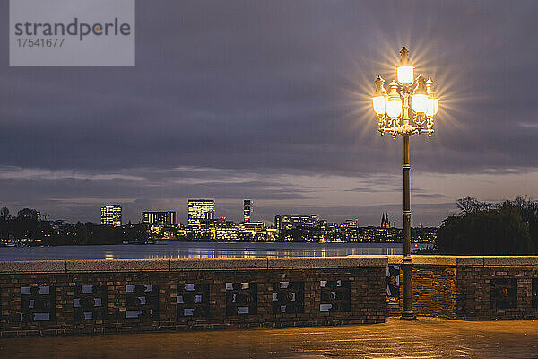 Germany  Hamburg  City skyline seen from Krugkoppelbrucke bridge at night with street light glowing in foreground