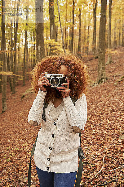 Woman photographing through camera in autumn forest