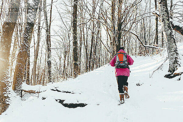 Mann läuft auf schneebedecktem Land im Wald