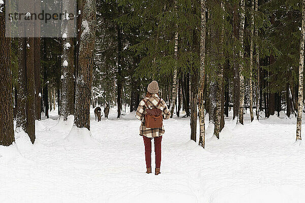 Frau mit Rucksack steht auf Schnee im Winterwald
