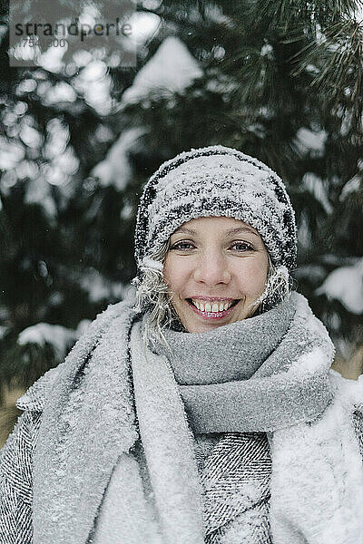 Happy woman wearing snowy knit hat in public park
