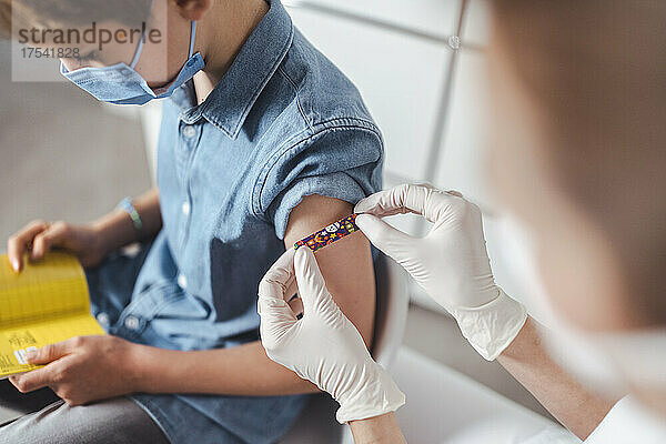 Krankenschwester legt im Impfzentrum einen Klebeverband am Arm des Jungen an