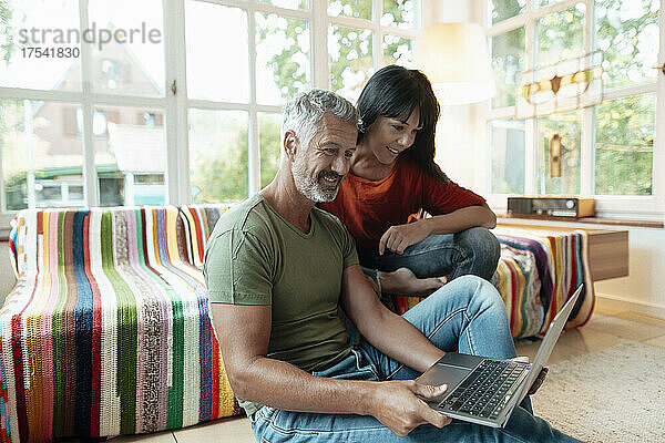 Lächelndes älteres Paar  das zu Hause einen Laptop benutzt