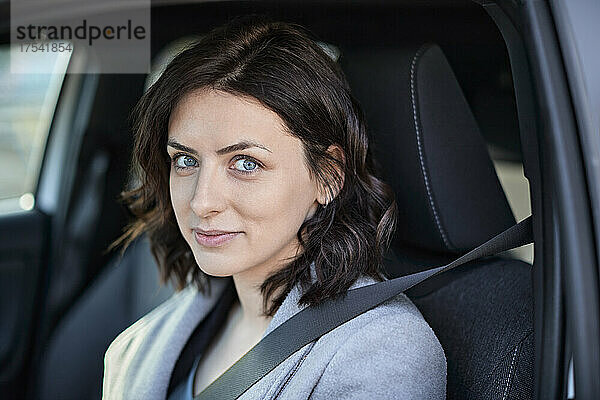 Lächelnde Frau sitzt auf dem Fahrersitz in einem Elektroauto