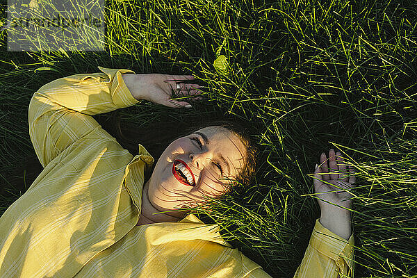 Carefree woman lying on grass laughing