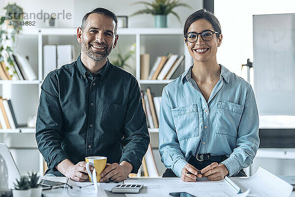Smiling businessman and businesswoman at desk in small office