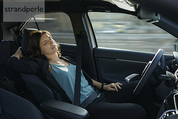 Müde Geschäftsfrau schläft im autonomen  fahrerlosen Auto