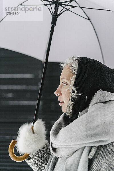 Nachdenkliche Frau mit Regenschirm im Winter