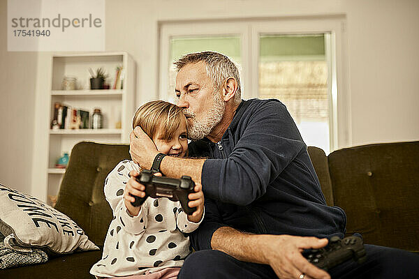 Großvater küsst Enkelin mit Joystick zu Hause
