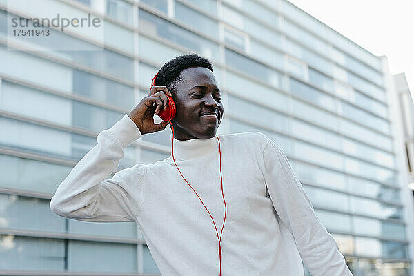 Smiling young man listening music through orange headphones