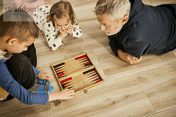 Grandfather playing backgammon with grandchildren at home